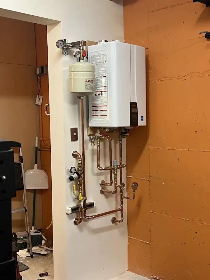 Plumbing technician inspecting water heater connections in Avon